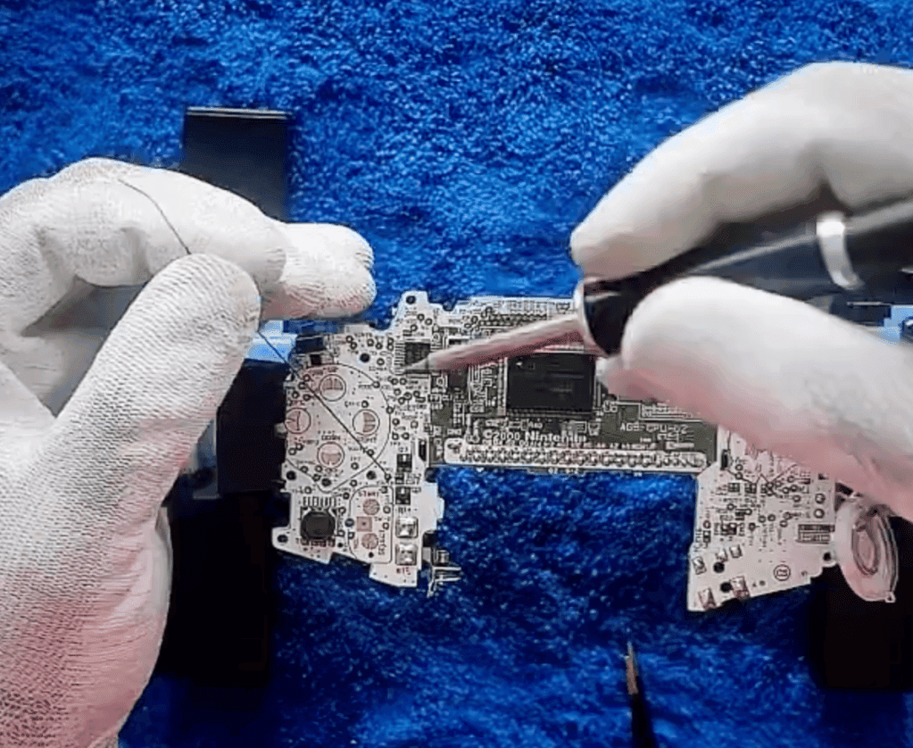 RetroGear-Moddingtechniker, der eine Nintendo Game Boy Advance-Mainboard lötet, während er weiße Handschuhe trägt.